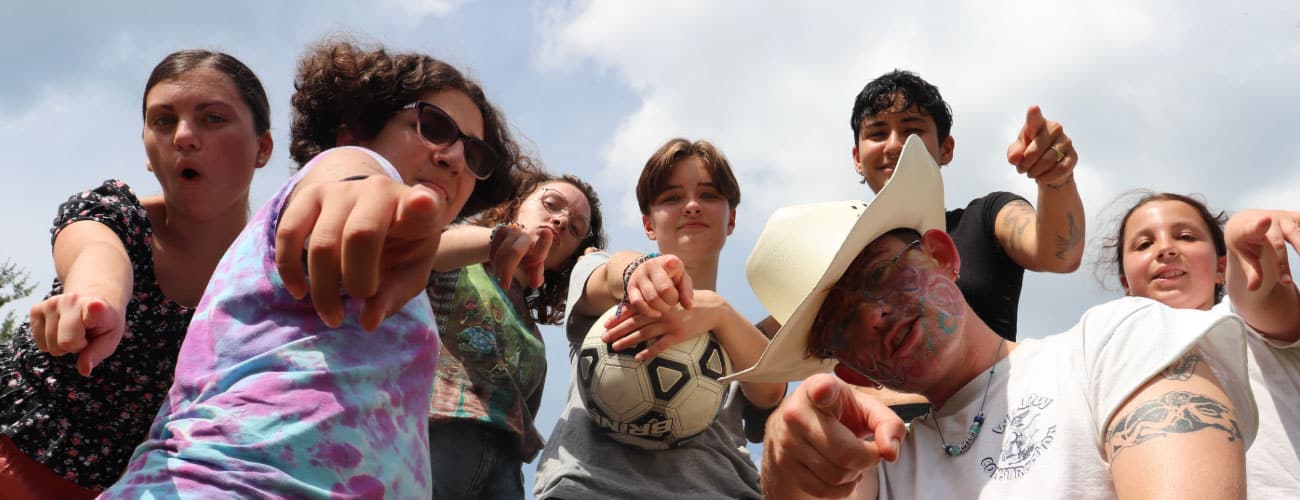 Teens at camp pointing down towards the camera