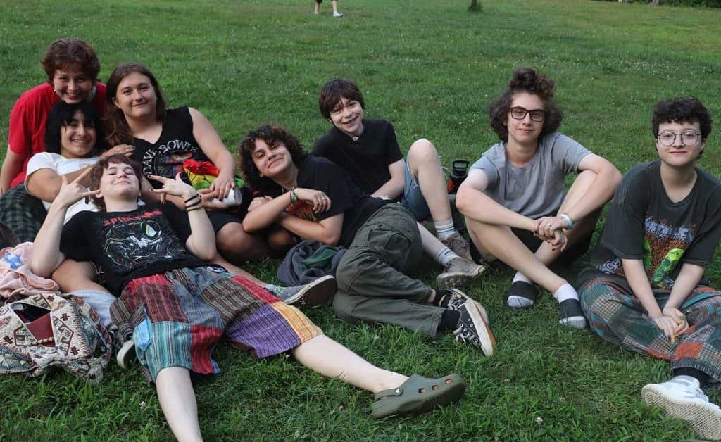 Group of teens on grass hanging out relaxing together