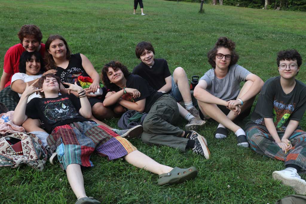 Group of teens on grass hanging out relaxing together